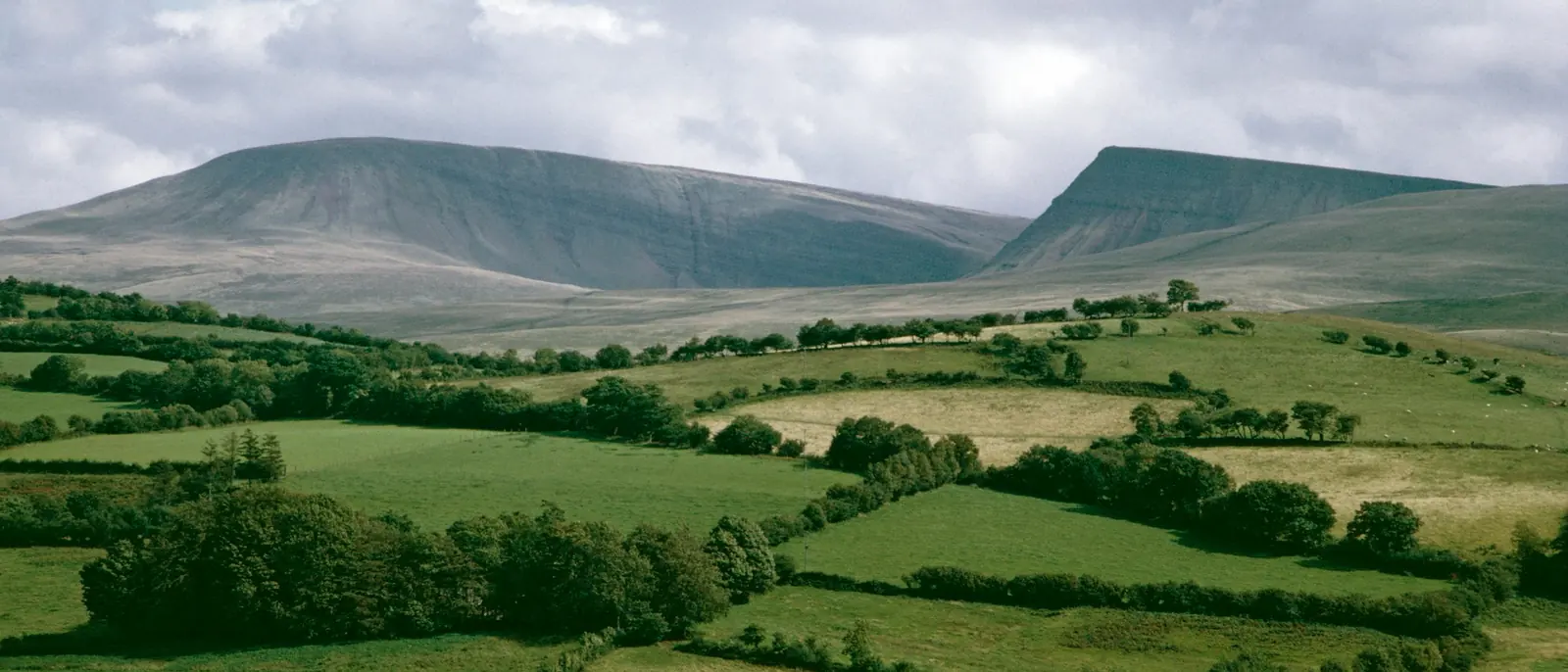 A South Wales valley of hedgerow fields below a flat-topped escarpment.